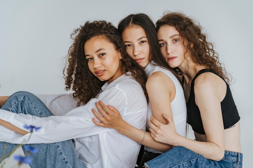 Three diverse women embracing, symbolizing friendship and togetherness.